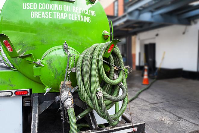 a technician pumping a grease trap in a commercial building in Ashton